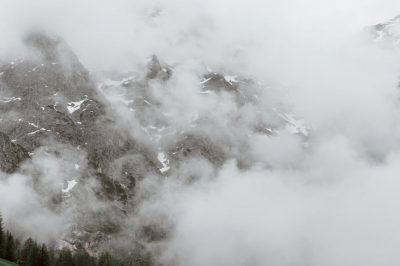 slope with houses against mountains in clouds