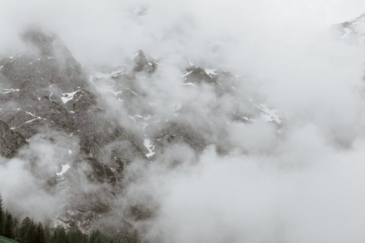 slope with houses against mountains in clouds